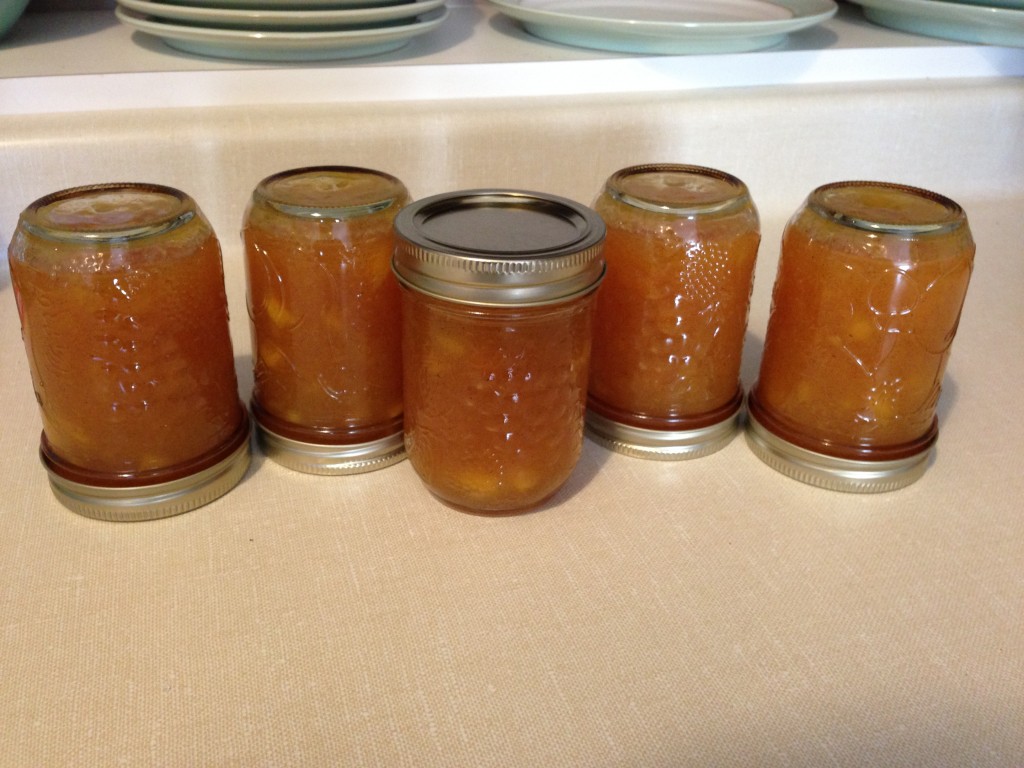 Peach jam jars sitting upside down on the counter.